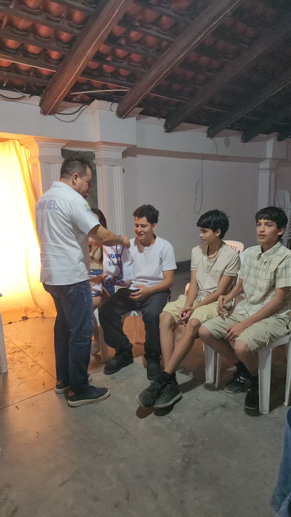 Rommel Durán saludando a jóvenes sentados durante una visita comunitaria