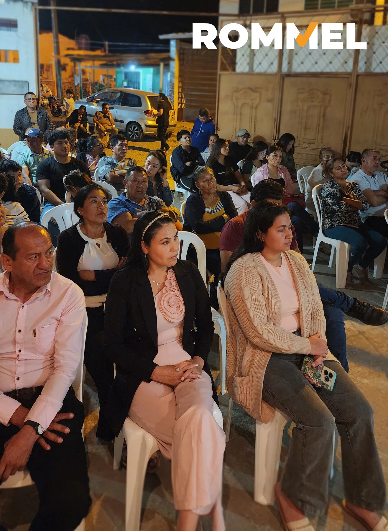 Asistentes atentos durante una reunión ciudadana nocturna