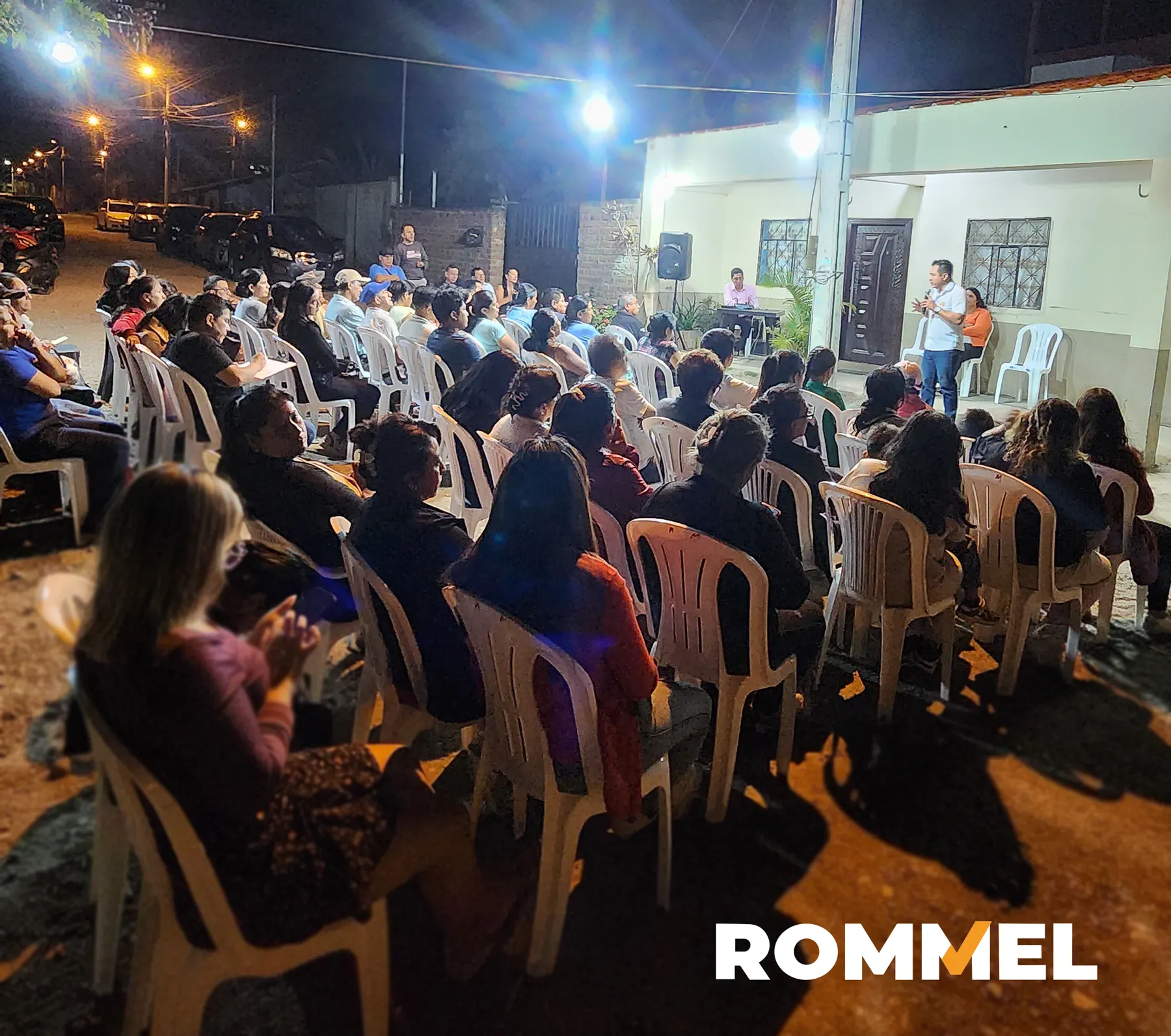 Familias sentadas en una reunión comunitaria al aire libre