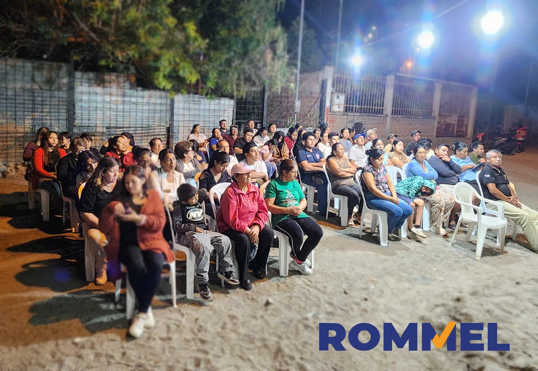 Amplio grupo de asistentes reunidos al aire libre durante la noche